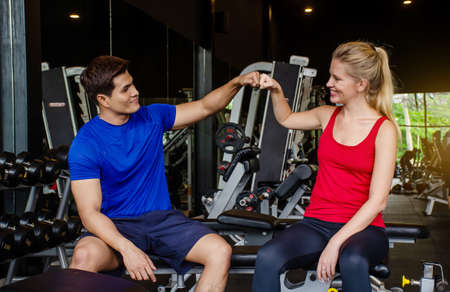 Young Sport man and girl or couple training fitness in sport gym with making Hi-5 with happy at gym, Fitness exercise and healthy concept.の写真素材