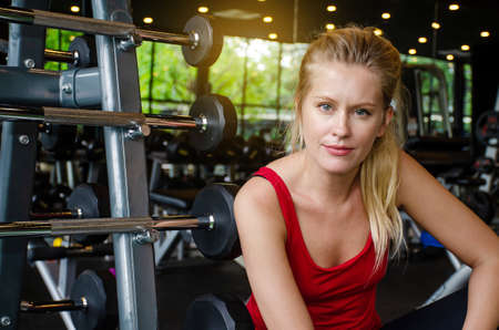 Fit adult woman resting in gym after a hard workout, Beautiful woman sitting at the gym smiling, Fitness concept.の写真素材