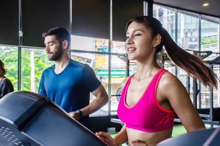 Active young woman and man workout of Running on treadmills in gym healthy lifestyle