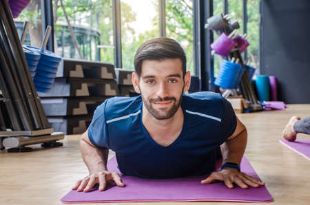 Portrait of young sporty man practicing yoga, lying in Cobra pose, doing Bhujangasana exercise, Calmness and relax male happiness, working out at home or in modern yoga studioの写真素材