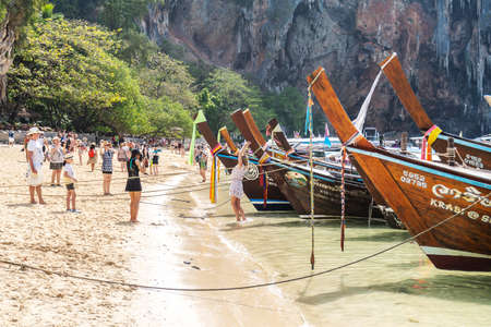 Railay, Thailand - February 15, 2020: Thai traditional long boats on crowded Phra Nang Cave Beach, Railay in Krabi province, Thailand. Tropical beach of Andaman Sea with walking tourists.のeditorial素材