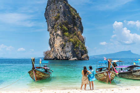 Railay, Thailand - February 15, 2020 : Two woman tourist and long tail boats on the beautiful sand beach at Koh Poda island in Krabi province. Ao Nang, Krabi island is a most popular tourist destination in Thailandのeditorial素材