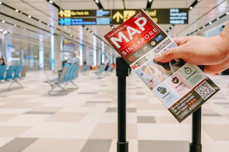 SINGAPORE - NOVEMBER  22, 2018: Passengers holding travel luggage with map at the airportのeditorial素材