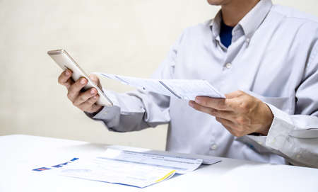 Businessman holding so many expenses bills such as electricity bill, water bill,internet bill,cell phone bill and credit card bill in his hand, Calculation of costsの写真素材