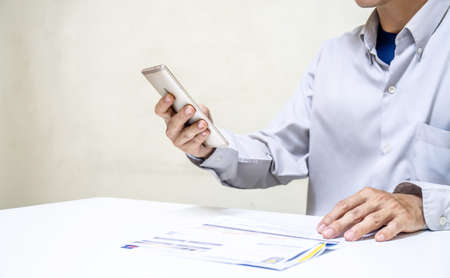 Businessman holding so many expenses bills such as electricity bill, water bill,internet bill,cell phone bill and credit card bill in his hand, Calculation of costsの写真素材