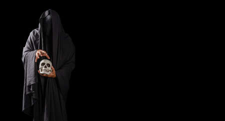 Portrait of a mysterious black man holding a skull in his hand isolated on black backgroundの写真素材