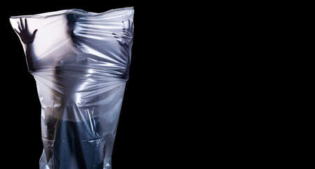A man covered with a white shroud like a ghost shows horror isolated on black background with copy space, Halloween and horror, with clipping pathの写真素材