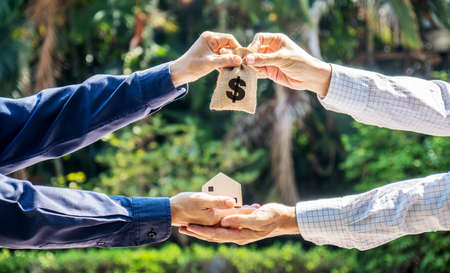 Model house and money bag in the hands of investors.Save money for buying a new home and borrowing money to plan the real estate investment in the future on park background.の写真素材