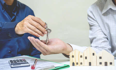 Real estate agent giving house key to customer. client signing mortgage loan contract agreement. buying selling renting real estate property,There is space for entering text.の写真素材