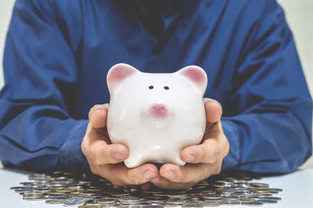 Close up of businessman holding piggy bank and money coin , saving money for future investment concept.の写真素材