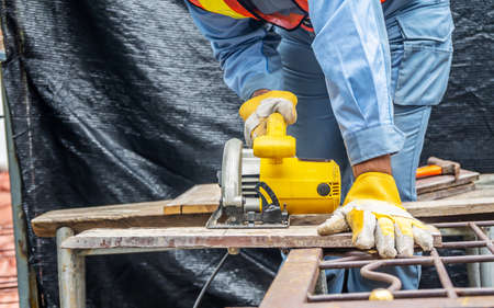 Carpenter using circular saw for cutting wooden boards with power tools, construction and home...