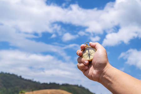 Male traveler man hand with compass on background of meadow mountains in summerの写真素材