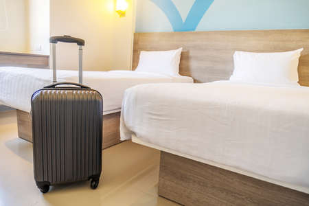 Black travel suitcase or luggage bag in a modern hotel room - relaxing time, holidays, weekend and traveling concept.の写真素材