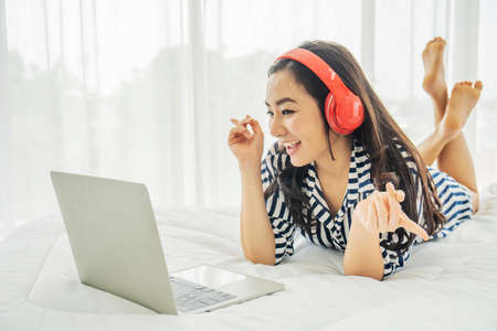 Beautiful asian woman relaxing and video call with her boyfriend while using laptop computer while being in social distance due to the covid-19 quarantine, She enjoying lifeの写真素材