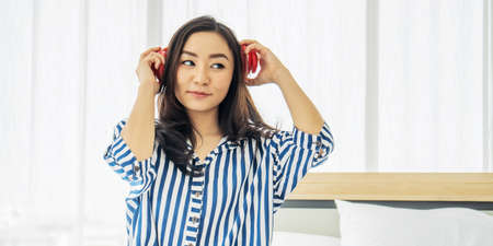 quarantine due coronavirus pandemic. stay at home. beautiful young woman relaxing and listening the music on the bed in bed room. Beauty asian girl gets happy, relaxing.の写真素材