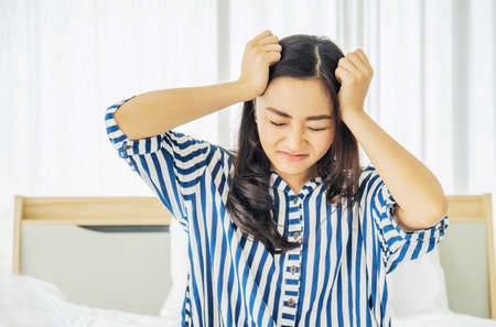 Beautiful Asian women touch head suffering from migraine or headache and feel strain and serious on bed, bad newsの写真素材