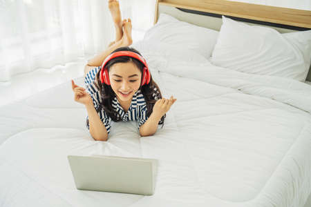 Beautiful asian woman relaxing and video call with her boyfriend while using laptop computer while being in social distance due to the covid-19 quarantine, She enjoying lifeの写真素材