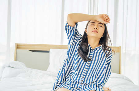 Beautiful Asian women touch head suffering from migraine or headache and feel strain and serious on bed, bad newsの写真素材