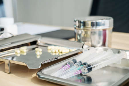Syringes and drugs on surgical tray with medical equipment on wooden table doctor at office room medical concept.の写真素材