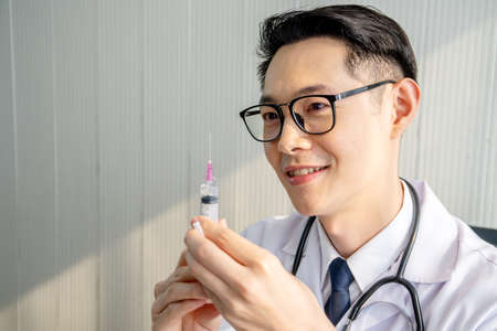 Man medical expert doctor shows syringe with medicine vaccine to a patient.の写真素材