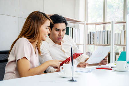 Image of two young business woman and man discussing questions while using computer at workplace in modern office. Teamwork, meeting and brainstorming conceptの写真素材