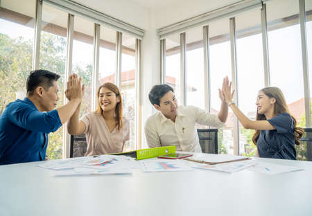 Diverse business team celebrating and giving high fives during boardroom meeting, - business celebration conceptの写真素材