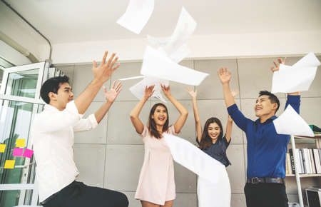 Group of young confident business people  happy smile celebrating  by throwing their business papers in the air, success team concept after sign contractの写真素材