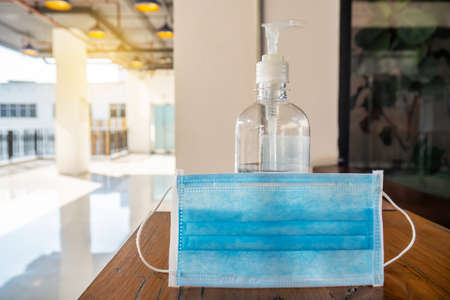 Corona virus or COVID-19 prevention concept, Medical surgical mask and hand sanitizer bottle on table for hand hygiene to help stop spreading outbreak coronavirus covid-19 for public health safetyの写真素材