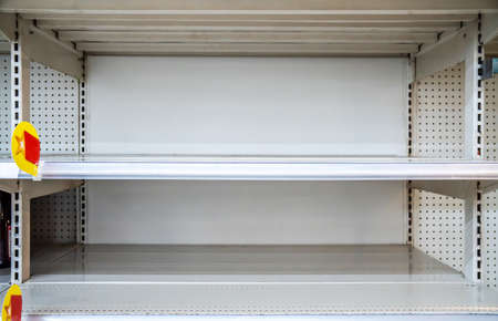 A view of empty shelves at a department store or supermarket after fear and panic shopping because of Covid-19, Hoarding food due to Coronavirus outbreak. Food shelf has been wiped out from panic buyingの写真素材