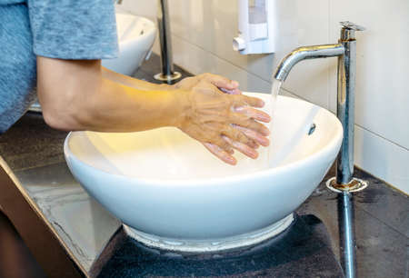 Corona virus or COVID-19 prevention concept, Corona virus travel prevention man showing hand hygiene washing hands with soap in hot water for coronavirus germs spreading protection.の写真素材