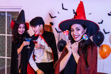 Asian Happy friends in costumes and makeup on a celebration of Halloween eating lollipop with drinking cocktails and having fun in party, Celebration of Halloween.の写真素材