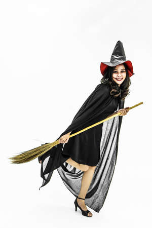 Halloween party Girl wearing witch costume with a hat, Celebrating. Beauty asian woman with long hair standing and smiling holding  broomstick isolated on white background.の写真素材