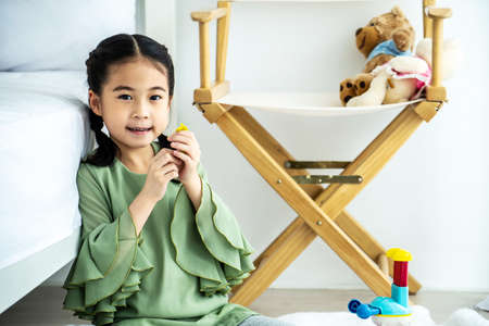 Happy Asian baby girl playing with colorful clay molding different shapes on the floor in the bedroom. Home activities for family.の写真素材