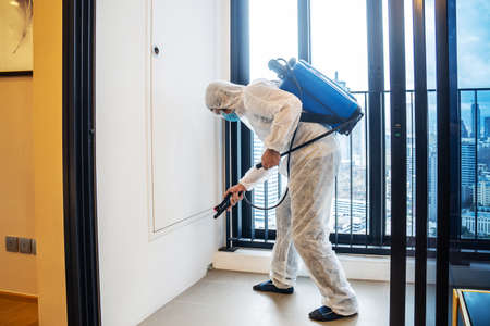 Asian man in protection germ suit or PPE suit  to protect against COVID-19 using nebulizers, Face shield, Mask, and Alcohol gel for cleaning place and use chemicals disinfecting in balcony, quarantine, disinfectionの写真素材