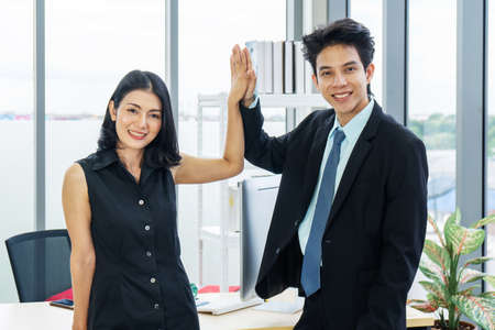 Well done! Smiling asian female and male company colleagues giving high five in office, excited with starting partnershipの写真素材