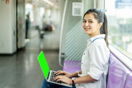 Beautiful asian woman working urgently on a laptop computer at the 
electric train in the morningの写真素材