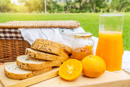 Summer picnic with fruits and bread and jam. Picnic in the park with orange juice and picnic basket. Fresh fruit in nature. A date for two in the parkの写真素材