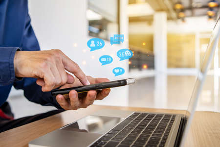 Customer support hotline Contact us people connection. Businessman using a social media marketing concept on mobile with notification icons of like, message, comment and star above smartphone screenの写真素材