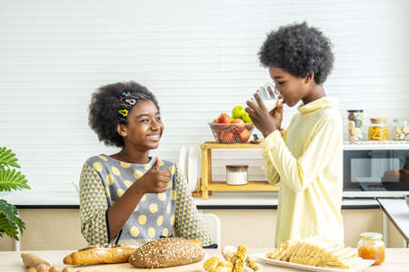 Two cute adorable siblings african american children having breakfast with milk at kitchen, Portrait of happy brother drinking milk with his sister and thumbs up, Food and drink conceptの写真素材