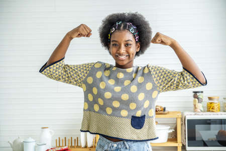 Young happy woman african american afro hair standing and  making strong hand while drinking a milk for breakfast with funの写真素材