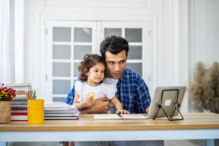 Father and daughter at home eating a slice of pizza food online together with her mother in video conference with digital tablet for a online meeting in video call for social distancingの写真素材
