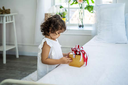 Pretty little girl happily after receiving the gift box in bed from her parents. due to birthday, Happy Holidays. Gift and presentの写真素材