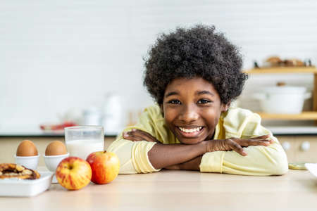 Close up smiling little boy drink glass of milk, sitting at wooden table in kitchen, adorable child kid enjoying organic food yogurt, getting vitamins and calcium, children healthcare conceptの写真素材
