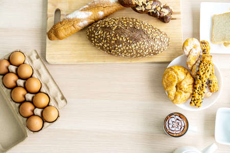 Fresh homemade baked bread with butter served as breakfast on white table with boiled eggs and milk...