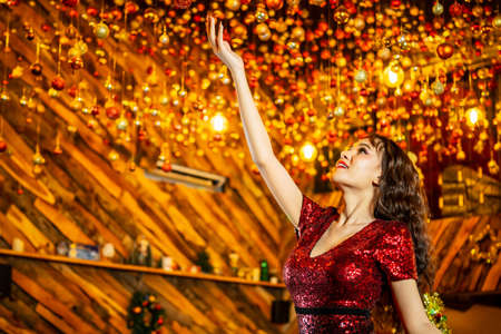 merry xmas and happy new year are coming, Asian woman decorating colored balls and glowing lights on ceiling, young girl cheerful preparing for christmas eve concept.の写真素材