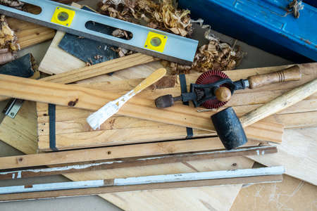 Background image of carpenters workstation, carpenters work table with different tools, wood cutting, water level gauge, paint brush with wood shavingsの写真素材