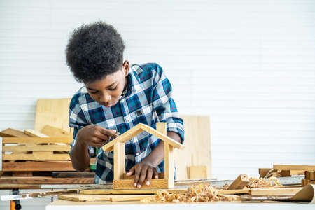 Smiling kid carpenter happy working with wood and sandpaperの写真素材