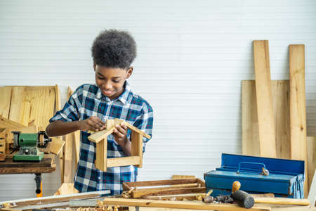 Smiling kid carpenter happy working with wood and sandpaperの写真素材