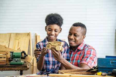 Happy family african american father and son carpenter gather craft a car out of wood and play, family concept to stay at home and enjoy good relationship hobby together craftsman or carpenterの写真素材