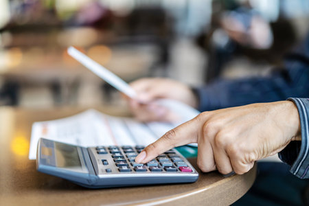 Accounting businessmen are pressing the calculator calculate the various costs that must be paid by the bill, Many invoices held and placed on the table, Financial and tax systems concept.の写真素材
